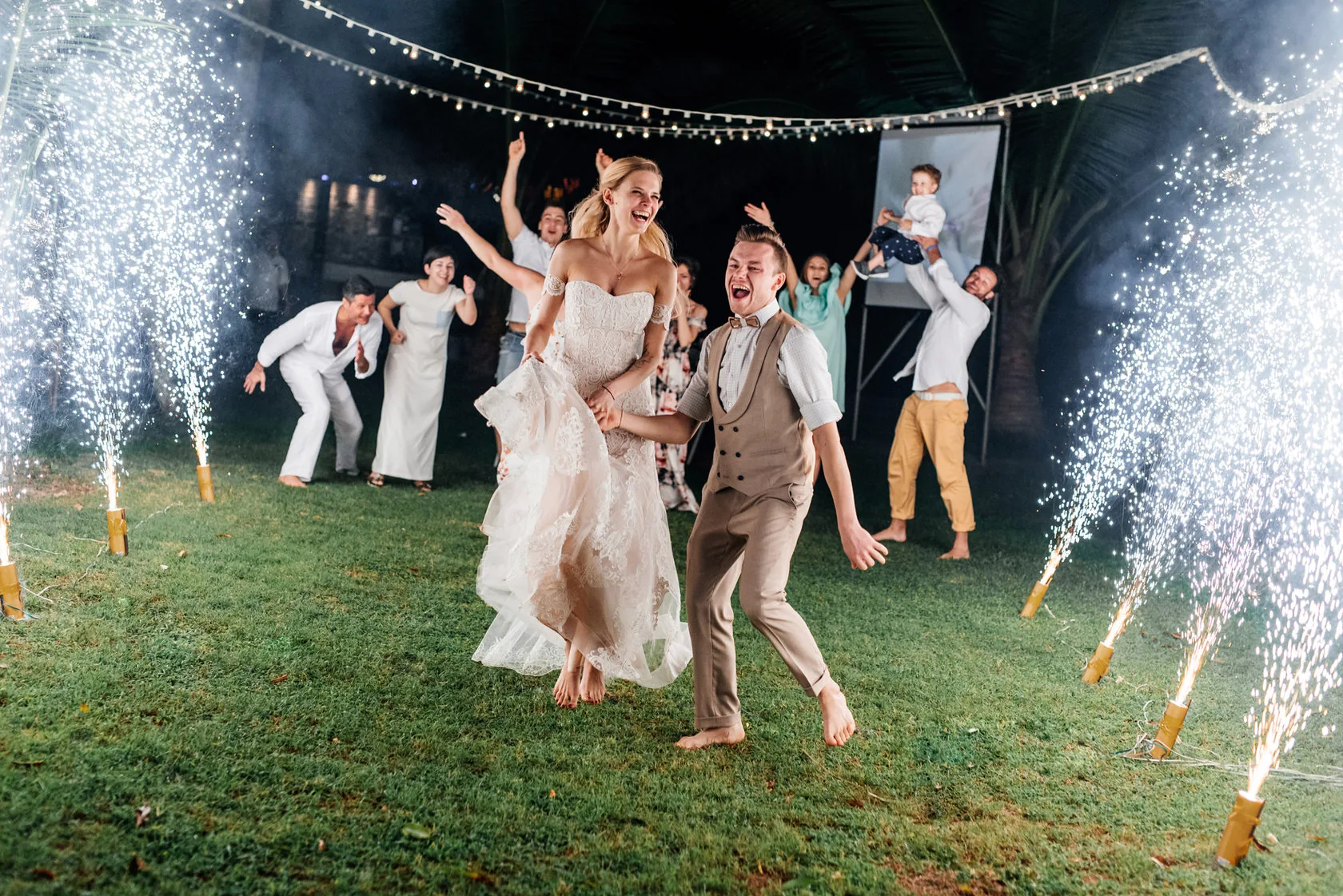 Bride and groom celebrating at night between spark fountains
